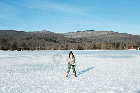 穿着溜冰鞋站在雪地里的女孩背景图片
