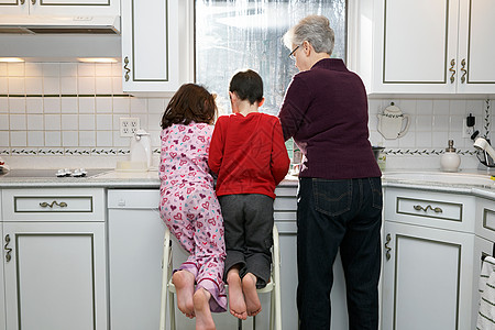 带着男孩和女孩的祖母在厨房，后视图图片