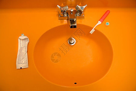 带牙刷和牙膏的橙色水槽背景图片