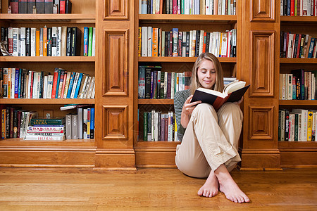 坐在书架上看书的年轻女子图片
