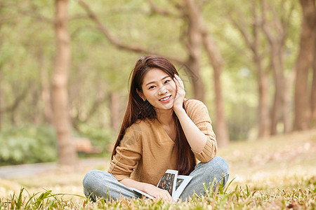 年轻女性坐在草地上看书 图片