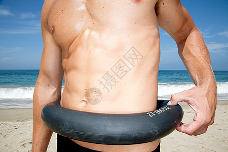 沙滩上的男人在腰间捏轮胎图片