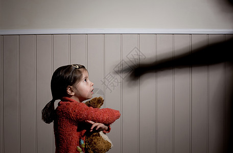 3岁孩子吓坏了的小女孩和大人用手指着她的影子背景