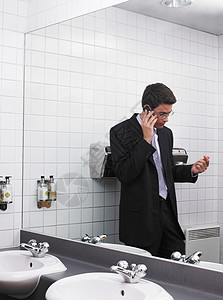 用手机反射在办公室卫生间镜子里的男人图片
