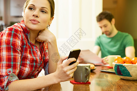 年轻夫妇吃早饭时候女人用智能手机图片