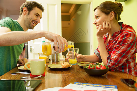 年轻夫妇吃早饭,男人倒橙汁图片