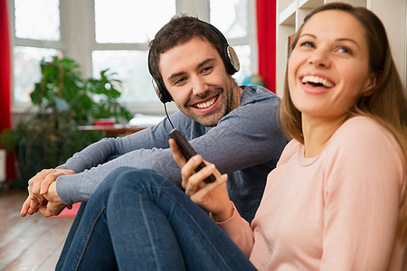 年轻夫妇笑着,戴着耳机的男人图片