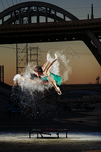 美国洛杉矶日落时分女芭蕾舞演员在蹦床上跳同时释放出粉末爆炸图片