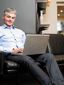 坐在沙发上用笔记本电脑的男人图片