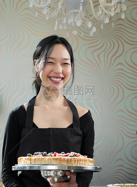 年轻的女服务员微笑着拿着甜点图片