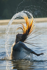 年轻女子在水中甩湿头发的侧视图图片