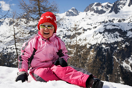 穿着粉红色衣服的女孩坐在雪地里图片