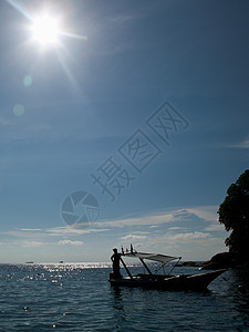 马来西亚提奥曼岛阳光下站在靠码头的船上的人图片