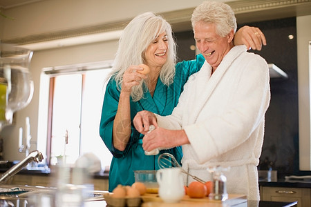 穿着浴袍做饭的老年夫妇图片