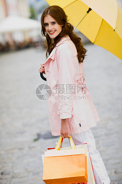 一个拿着购物袋在撑伞的女人图片