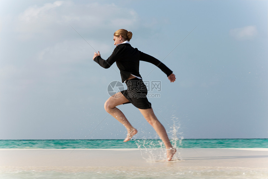 在海滩跑步的女商人图片