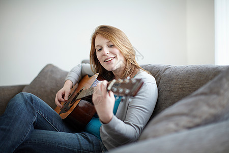 坐在沙发上弹吉他的女孩图片