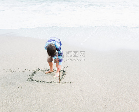 男孩在沙地上画正方形图片