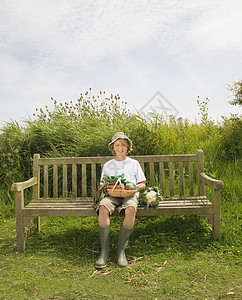 男孩坐在长凳上，拿着蔬菜图片