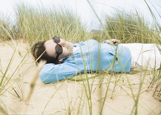 戴着太阳镜躺在沙丘上的女人图片