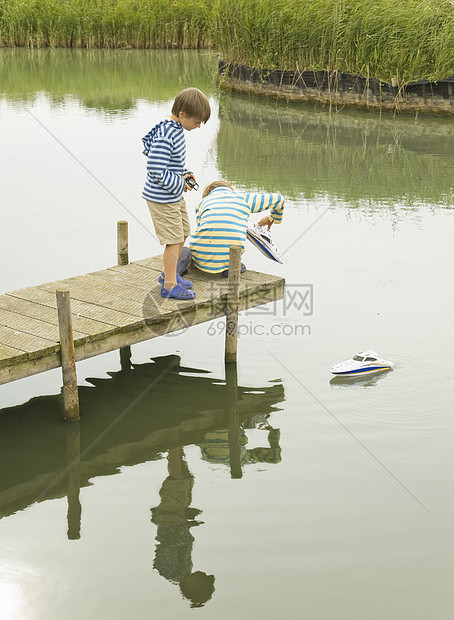 男孩们在码头上玩玩具船图片