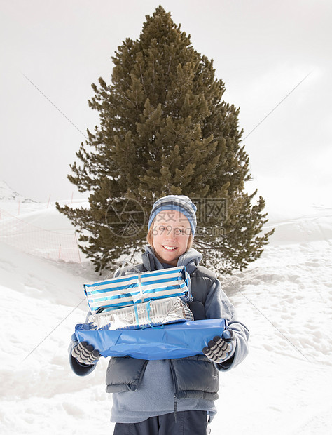 男孩带着圣诞礼物在雪地里图片