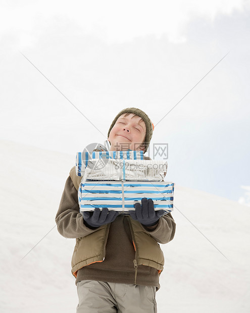 男孩拿着圣诞礼物在雪地里图片