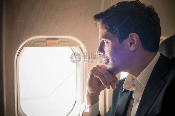 从飞机窗口向外看的男性乘客图片