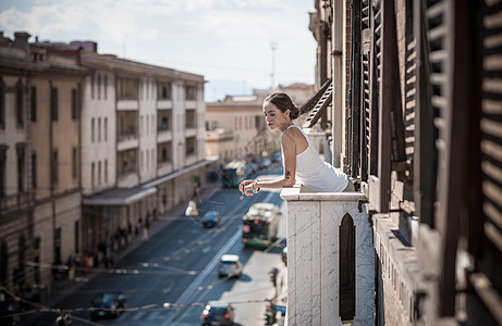 意大利撒丁岛卡斯蒂达斯，一名年轻女子从阳台上眺望街道图片