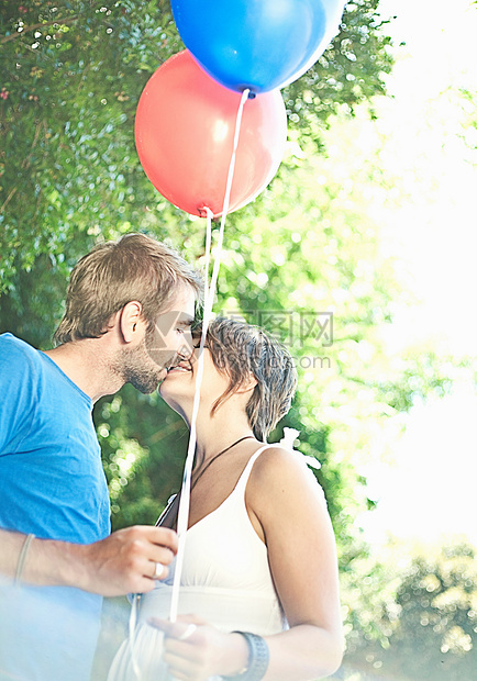 拿着气球在公园接吻的情侣图片