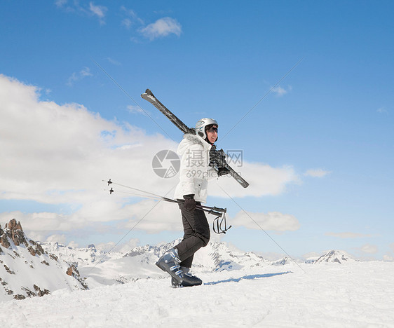 女人带着滑雪板在雪地里上山图片