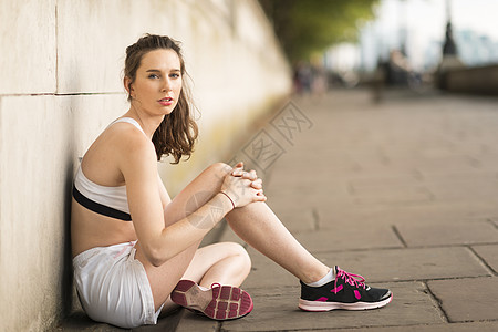 坐在河边的年轻女跑步者的肖像图片
