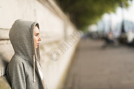 穿着灰色连帽上衣的年轻女性从河边向外看图片