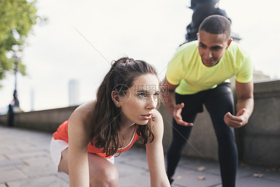 鼓励女性在河岸上跑步的年轻男教练图片