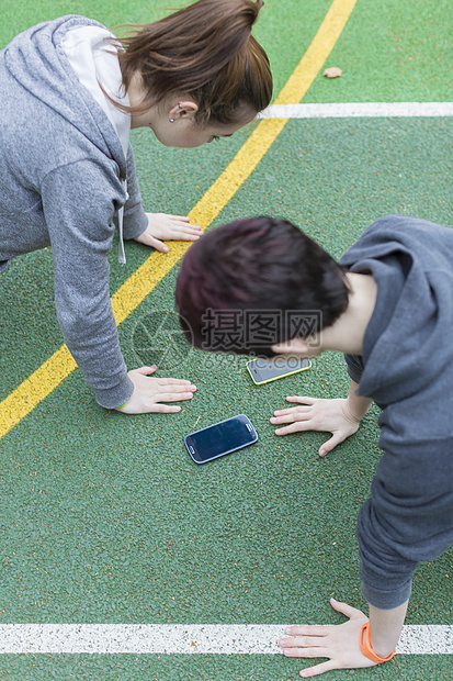 年轻女子在运动场上做俯卧撑图片