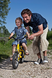 父亲帮女儿骑自行车图片