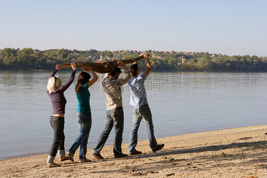 四个朋友抱着一根木头在湖边