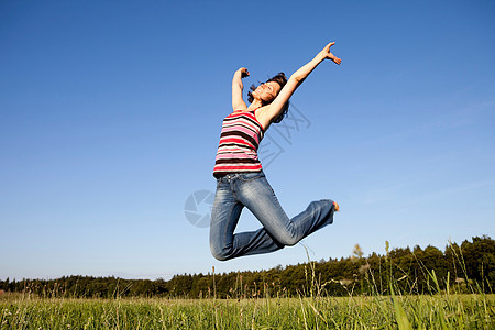 在草地上跳跃的女人图片