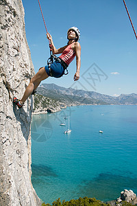 女子攀岩，背景为海湾图片
