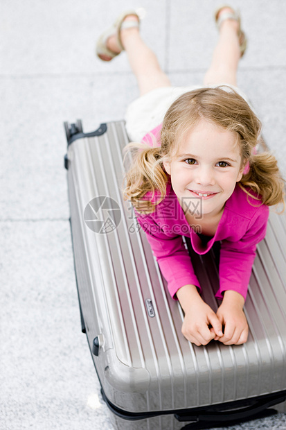 女孩微笑着靠在手提箱上图片