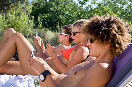 青年男女躺在阳光下玩手机图片