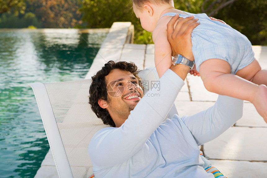 ‘~男人在泳池旁抱着婴儿  ~’ 的图片