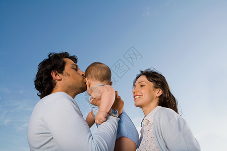 透彻的蓝天抱着孩子的夫妇背景