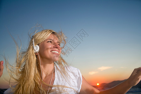 年轻女子日落时戴耳机图片
