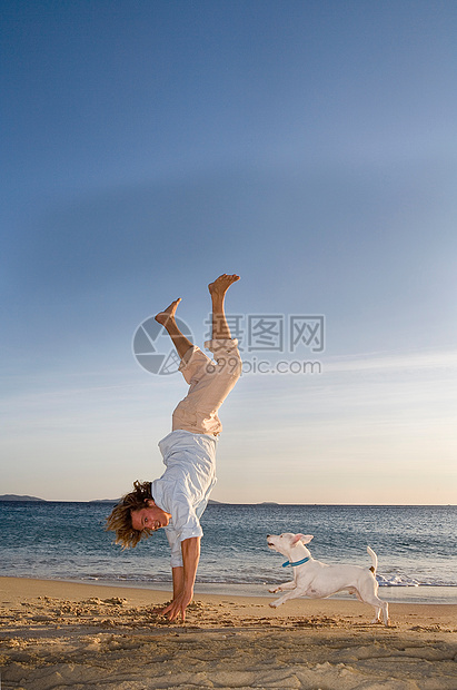 男人牵着狗站在海滩上图片