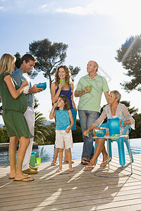 一家人在水池边的木平台上聊天喝饮料图片