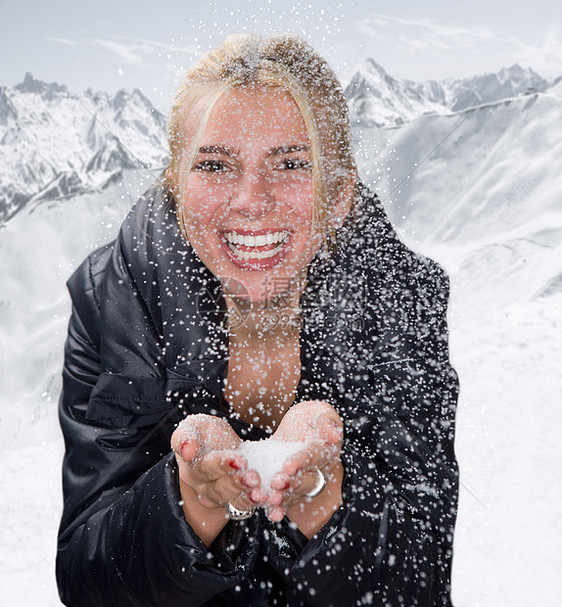 年轻的女人在雪地里捧着雪微笑图片