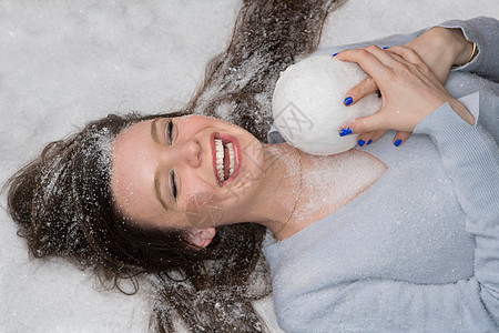 笑女人躺在雪地里抱雪球背景图片