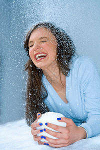 女人在雪地里笑，手里拿着雪球背景图片