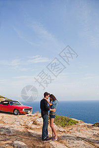 一对夫妇站在悬崖上的汽车前图片